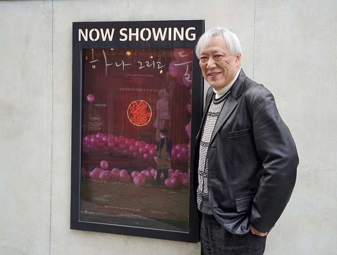 일본 영화 제작자 가와이 가와이가 지난 9일 서울 종로구 에무시네마에 걸려 있는 <하나 그리고 둘> 포스터 옆에서 포즈를 취하고 있다. 에무필름즈 제공