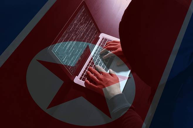 A hacker is seen in against a North Korean flag in this file image. [JOONGANG ILBO]
