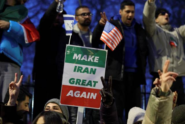 12일 영국 런던 이란 대사관 앞에서 열린 집회에 참석한 한 시민이 ‘이란을 다시 위대하게’라고 적힌 플래카드를 미국·이스라엘 국기와 함께 들어보이며 현재 이란 전역에서 확산하는 반정부 시위에 대한 지지를 표명하고 있다. 로이터 연합뉴스