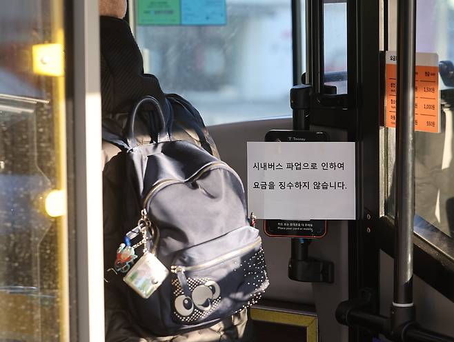 서울 시내버스 노동조합이 첫차부터 무기한 전면파업에 돌입한 13일 서울 홍제역 인근에서 운행 중인 한 버스에 '시내버스 파업으로 인하여 요금을 징수하지 않습니다'라는 안내문이 붙어 있다. 연합뉴스