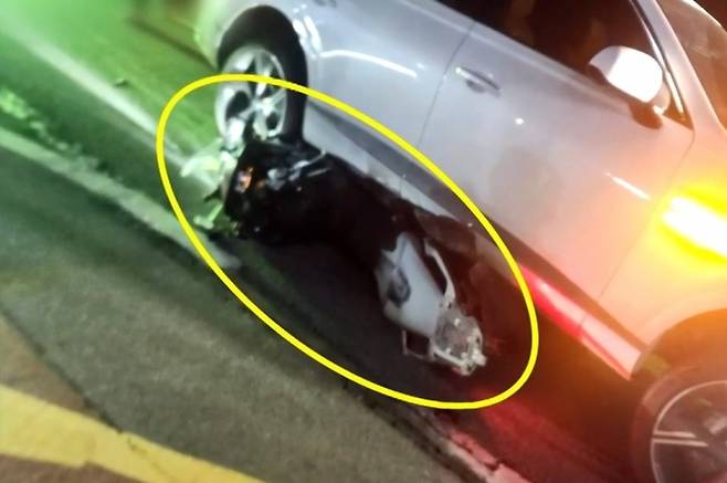 지난 4일 오후 9시쯤 충남 홍성 내포신도시 한 도로에서 오토바이를 몰던 30대 남성이 뒤에서 온 음주운전 차량에 치여 숨지는 사고가 발생했다. 사진은 가해 차량 아래에 깔려 있는 피해 오토바이. JTBC ‘사건반장’ 보도화면 캡처