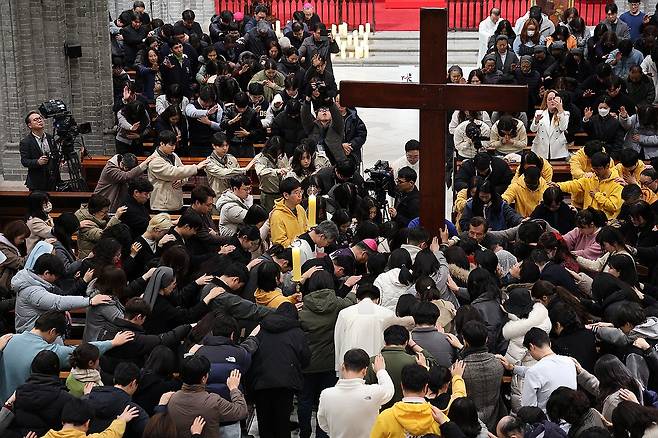 세계청년대회 상징 십자가·성화 명동대성당서 공개 (서울=연합뉴스) 29일 오후 서울 명동대성당에서 열린 '서울 세계청년대회(WYD) 십자가, 성화 환영의 밤'에서 참가자들이 WYD 상징물 십자가에 손을 올리고 기도하고 있다. 2024.11.30 [천주교 서울대교구 제공. 재판매 및 DB 금지] photo@yna.co.kr