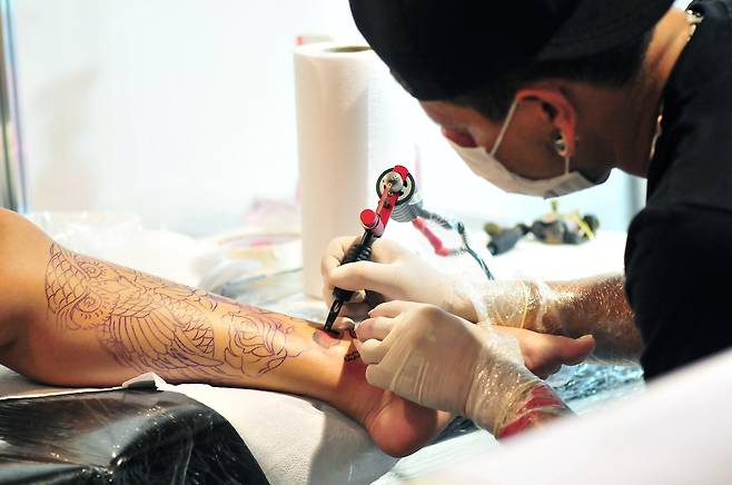 A tattoo artist works on a client's tattoo. This photo is not directly related to the story. (123rf)