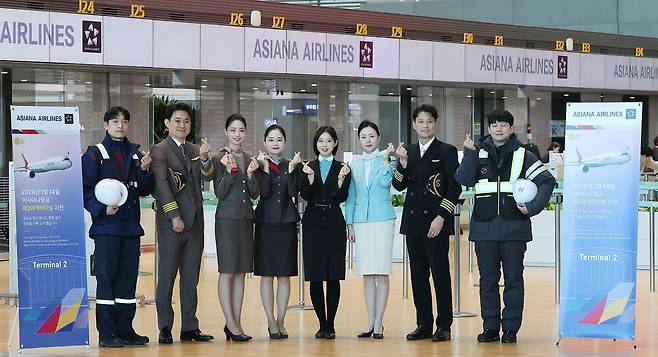 Asiana Airlines and Korean Air staff pose for a photo at Incheon International Airport Terminal 2 on Jan. 14, after Asiana moved its check-in counters and terminals as part of its integration with Korean Air. [JOINT PRESS CORPS]