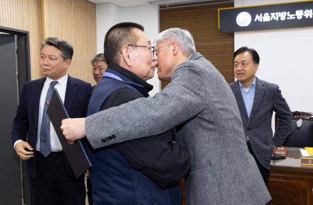 14일 오후 서울 영등포구 서울지방노동위원회에서 열린 특별조정위원회 2차 사후 조정회의에서 교섭을 타결한 박점곤(왼쪽) 전국자동차노동조합연맹 서울시버스노동조합 위원장과 김정환 서울시버스운송사업조합 이사장이 포옹하고 있다. 뉴시스