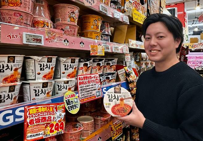 GS25가 PB라면 '오모리' 시리즈를 일본 돈키호테로 수출했다. 모델이 일본 돈키호테 매장에서 '오모리' 시리즈를 들고 포즈를 취하고 있다. /사진제공=GS리테일
