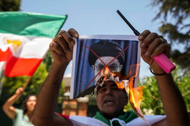 하메네이 사진 태우는 칠레 시위대 - 13일(현지시간) 칠레 산티아고 주재 이란대사관 주변에서 열린 이란 반정부 시위 연대 집회에 참석한 한 남성이 아야톨라 알리 하메네이 이란 최고지도자 사진을 태우고 있다. 산티아고 AP 뉴시스