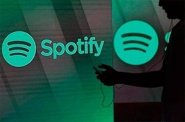 한 남성이 영국 런던의 스포티파이 로고가 새겨진 조명 앞에서 스마트폰 화면을 확인하고 있다.