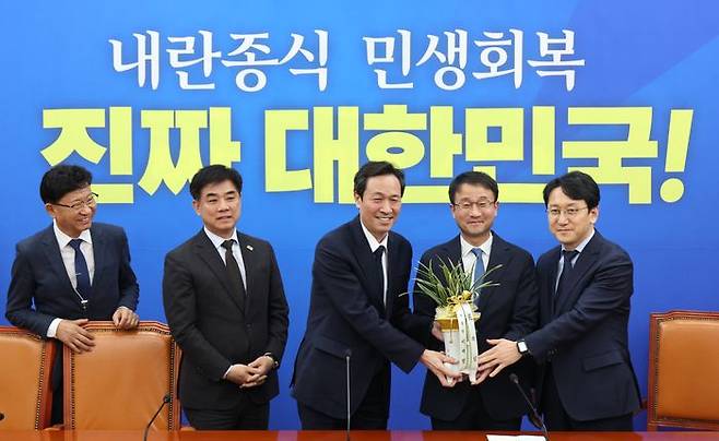 한병도 더불어민주당 원내대표가 12일 오후 국회에서 우상호 대통령실 정무수석에게 이재명 대통령이 보낸 축하 난을 건네받고 있다. 우 수석 왼쪽은 김병욱 정무비서관 ⓒ뉴시스