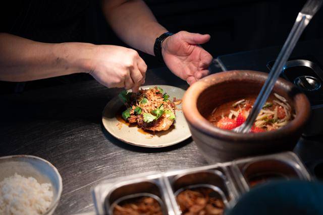 손승희 셰프가 '카이 룩 커이'를 접시에 옮겨 담고 있다. 카이 룩 커이는 튀긴 유정란과 피시소스, 샬롯 고수를 곁들인 요리다.