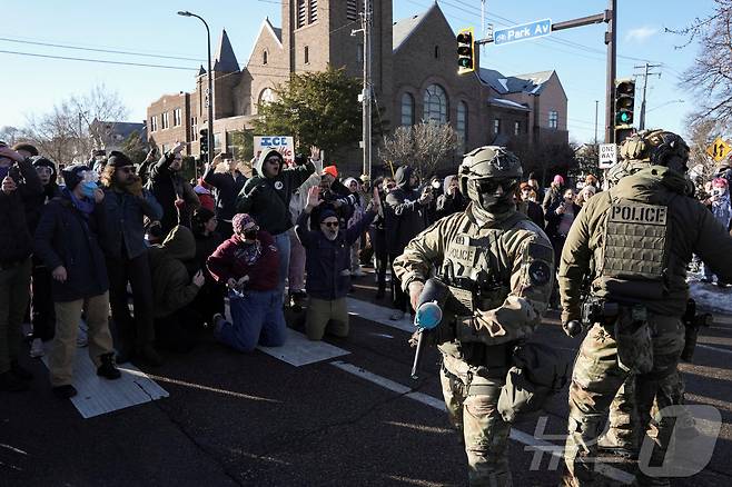 13일(현지시간) 미국 미네소타주 미니애폴리스에서 경찰과 시민들이 대치하고 있다. 일부 시민은 항의의 뜻으로 무릎을 꿇고 있다. 2026.01.13. ⓒ 로이터=뉴스1 ⓒ News1 권영미 기자