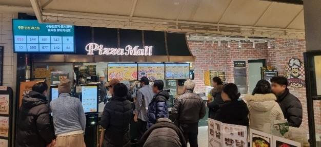 피자몰 NC강서점 앞에서 고객들이 줄지어 주문을 기다리고 있다.