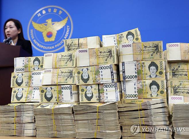 쌓여있는 범죄수익 현금다발  서울경찰청 광역수사단 금융범죄수사대는 2024년 3월 26일 허위 기업 상장 정보를 이용해 투자를 권유하는 수법으로 피해자 548명을 상대로 175억 원 상당을 편취한 비상장주식 판매 사기 범죄집단의 총책과 일당을 검거해 송치했다고 밝혔다. 사진은 서울경찰청 금융범죄수사대에 쌓여있는 41억여 원의 범죄수익 현금다발. 옆의 경찰은 김미애 금융범죄수사대 계장 
[이지은 기자]