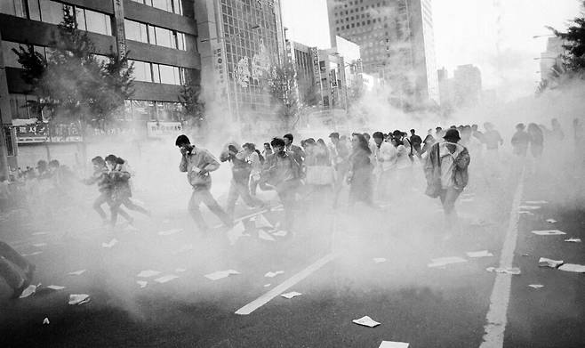 1991년 5월9일 ‘민자당 해체와 공안통치 종식을 위한 국민대회’ 예정 장소인 서울시청 앞 광장이 경찰에 원천봉쇄된 가운데, 저녁 7시 종로3가와 4가에 모인 시위대 3만여 명이 광화문 쪽으로 행진을 벌이다 경찰이 쏜 다연발 최루탄을 피하고 있다.