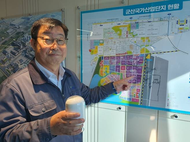 윤해구 PKC 대표가 사료 원재료 중 하나인 HCl-라이신 합성제품을 들고 군산 공장 위치를 가리키고 있다.