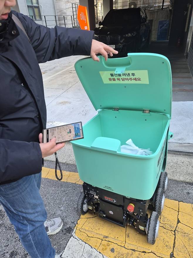 13일 서울 논현동에서 소비자가 배달로봇 딜리에서 주문한 물품을 수령하고 있다. 김현이 기자