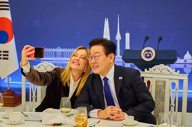 이재명 대통령과 조르자 멜로니 이탈리아 총리가 19일 청와대 본관에서 열린 공식오찬장에서 함께 셀카를 찍고 있다. 멜로니 총리가 들고 있는 스마트폰은 이 대통령이 이날 선물한 분홍색 삼성 갤럭시 Z플립 7 스마트폰이라고 청와대는 밝혔다. 청와대 제공