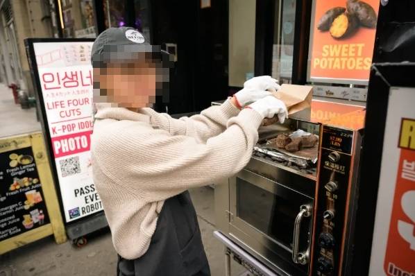 뉴욕 코리아타운의 한 식당 앞에서 군고구마를 굽고 있는 여성. 출처=뉴욕포스트