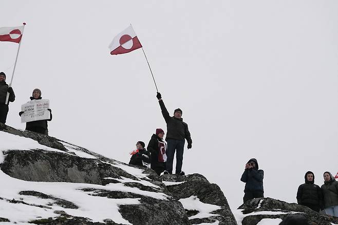 People wave Greenlandic flags as they take part in a demonstration that gathered almost a third of the city population to protest against the U.S. President's plans to take Greenland, on January 17 in Nuuk, Greenland. U.S. President Donald Trump escalated his quest to acquire Greenland, threatening multiple European nations with tariffs of up to 25 percent until his purchase of the Danish territory is achieved. Trump's threats came as thousands of people protested in the capital of Greenland against his wish to acquire the mineral-rich island at the gateway to the Arctic. [AFP/YONHAP]