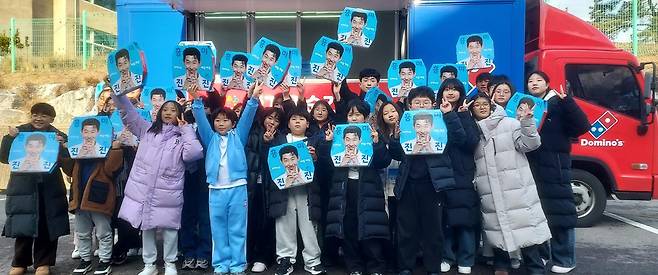 도미노피자는 지난 10일 NGO '사랑의달팽이'에서 진행한 클라리넷앙상블 겨울 음악캠프에 파티카를 통해 피자를 전달했다고 밝혔다. 사진은 피자를 들고 기념 촬영하는 모습. /도미노피자 제공