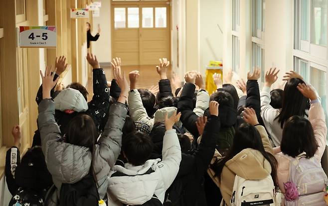24일 부산의 한 초등학교 학생들이 겨울 방학식을 마치고 교실을 나서며 선생님과 인사하고 있다. 연합뉴스