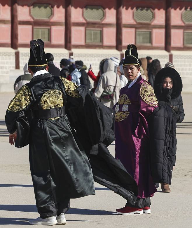 서울 전역에 한파주의보가 내려진 21일 서울 종로구 경복궁에서 외국인 관광객들이 기념사진을 찍은 뒤 외투를 입고 있다.