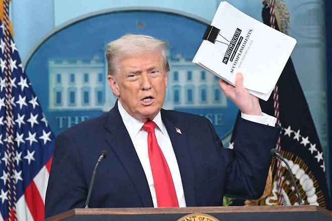 도널드 트럼프 미국 대통령이 집권 2기 취임 1주년인 20일(현지시간) 워싱턴DC 백악관에서 언론 브링핑을 열고 “우리는 그 어느 행정부보다 훨씬 더 많이 이룩했다”며 자찬했다. 이날 트럼프 대통령은 표지에 업적(accomplishment)이라고 적힌 두꺼운 종이 뭉치를 들고 나와 1시간 20분간 혼자서 외교, 경제, 사회 정책 등에 대해 장황하게 설명했다. [AFP]