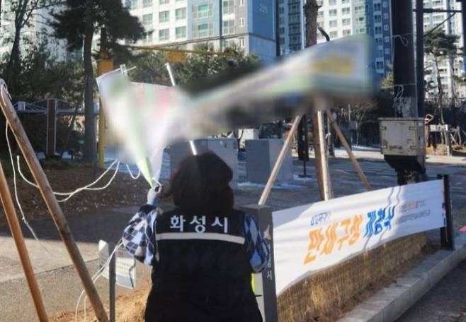 화성시 관계자가 도로변에 붙은 불법 현수막을 철거하고 있다. 화성시 제공
