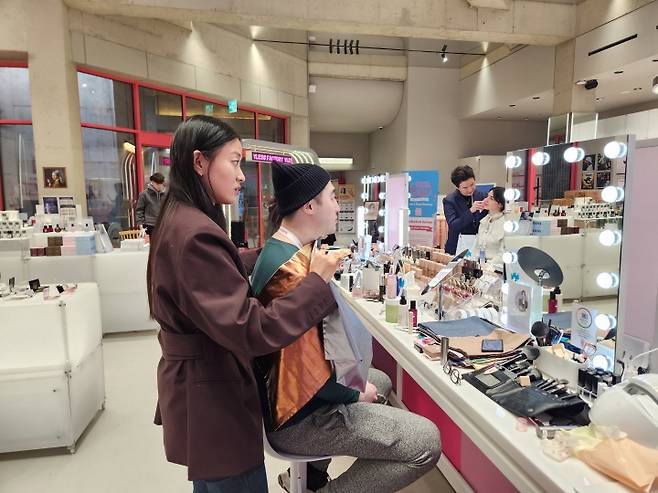 외국인 남성이 전문가의 설명을 들으며 퍼스널 컬러 진단을 받고, 자기&nbsp;피부와&nbsp;어울리는 색에 대해 조언을 듣고 있다.