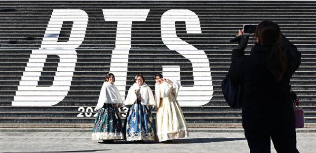 22일 서울 종로구 세종문화회관 계단에서 일본인 관광객이 3월 '완전체'로 돌아올 예정인 방탄소년단(BTS)의 컴백을 알리는 홍보물을 배경으로 기념사진을 촬영하고 있다. 연합뉴스