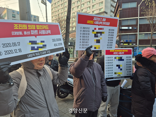 국민의힘 동작갑 당협위원회가 지난 14일 오후 서울 동작구 김병기 의원 지역사무실 인근에서 개최한 ‘김 의원 사퇴 촉구’ 집회 참가자들이 조진희 전 동작구의원·이지희 동작구의원의 법인카드 사용 내역 손팻말을 들고 구호를 외치고 있다. 김태욱 기자