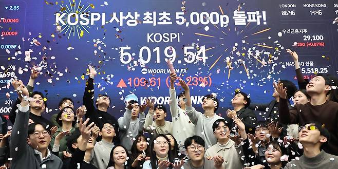 Traders celebrate the benchmark Kospi surpasing the 5,000-point mark for the first time, reaching 5,019.54 at the dealing room of Woori Bank's headquarters in Jung-gu, Seoul, Thursday. (Yonhap)