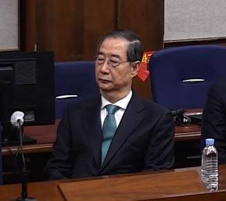 Former Prime Minister Han Duck-soo attends the first-instance sentencing hearing on charges of aiding the ringleader of an insurrection and playing a key role in the insurrection at the Seoul Central District Court in Seocho District, southern Seoul, on Jan. 21. [SCREEN CAPTURE FROM SEOUL CENTRAL DISTRICT COURT VIDEO/NEWS1]