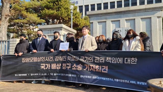 마산 모텔 흉기난동 사건 피해자 유가족들이 창원지법 정문 앞에서 소송장을 들고 있다./진휘준 기자/