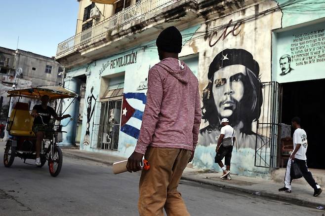 14일(현지시각) 쿠바 하바나에서 아르헨티나 출신 쿠바 혁명가 에르네스토 체 게바라의 벽화가 그려진 길을 한 주민이 걷고 있다. EPA 연합뉴스