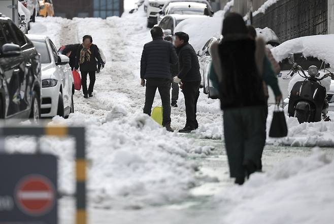 Pedestrians walk along an icy street near Dokkaebi Market in Uiwang, Gyeonggi Province. This photo is not directly related to the accompanying article. (Newsis)