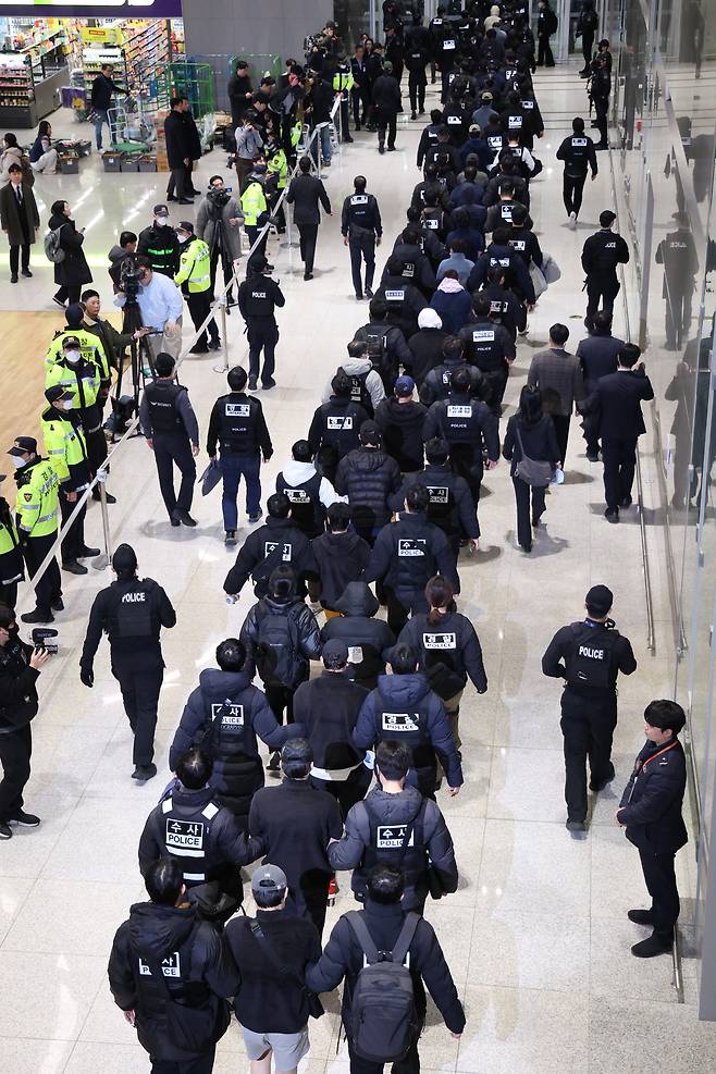 Police escort South Korean criminal suspects at Incheon Airport after their repatriation from Cambodia on Friday. (Yonhap)