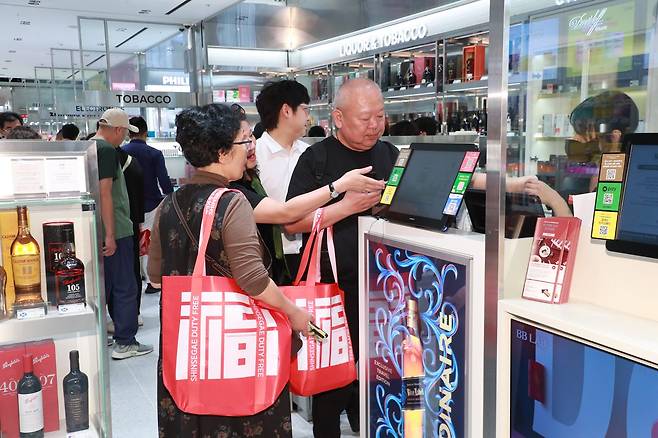 Tourists shop while carrying the eco-friendly “Fortune Bag.” [SHINSEGAE DUTY FREE]