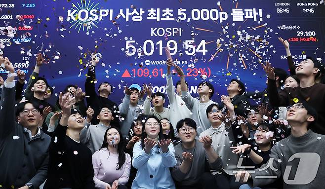 한국 증시가 사상 처음으로 '코스피 5000' 쾌거를 달성한 22일 서울 중구 우리은행 본점 딜링룸에서 직원들이 장중 최고가가 찍힌 전광판을 배경으로 코스피 5000 돌파를 축하하고 있다. 2026.1.22/뉴스1 ⓒ News1 오대일 기자