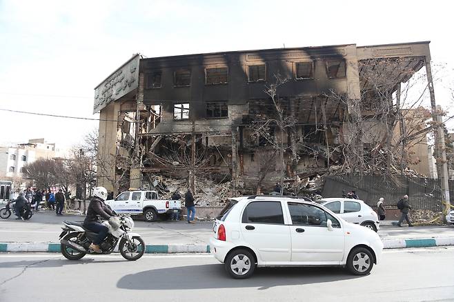 차량들이 지난 21일(현지시간) 이란 테헤란에서 최근 시위 과정에서 파괴된 세무서 건물 앞을 지나가고 있다. 신화연합뉴스