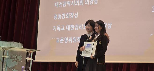 박창연 호수돈여중 교장이  송유빈 학생에게 대전시의회 의장상을 시상하고 있다.