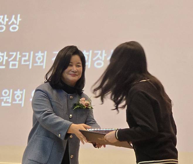김경미 교장이 최다연 학생에게 졸업생 대표에게 교육감상을 시상하고 있다.