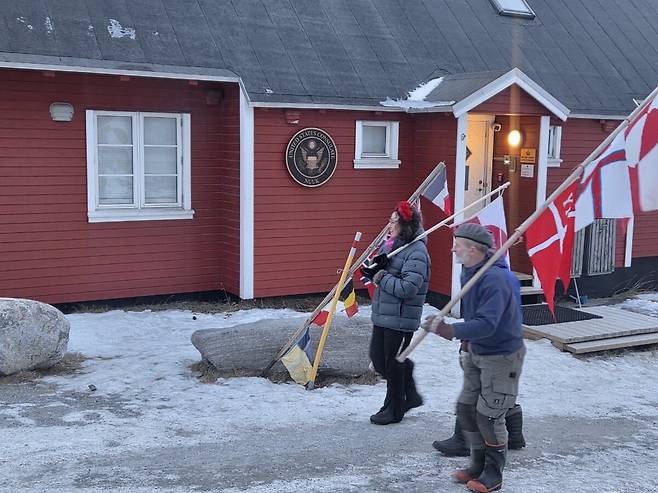 24일 그린란드 누크에 있는 미국 영사관 앞에서 그린란드 깃발을 든 주민들이 항의 행진을 하고 있다./연합뉴스