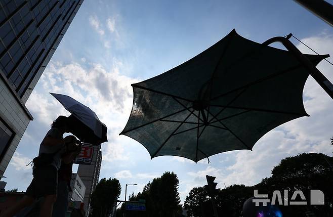 [서울=뉴시스] 황준선 기자 = 강남·서초·강동·송파구 등 서울 동남권에 폭염경보가 발효된 지난해 8월 25일 오후 서울 송파구 석촌호수 사거리에서 양산을 쓴 시민들이 발걸음을 옮기고 있다. 기사 내용과 관계 없음. 2025.08.25. hwang@newsis.com