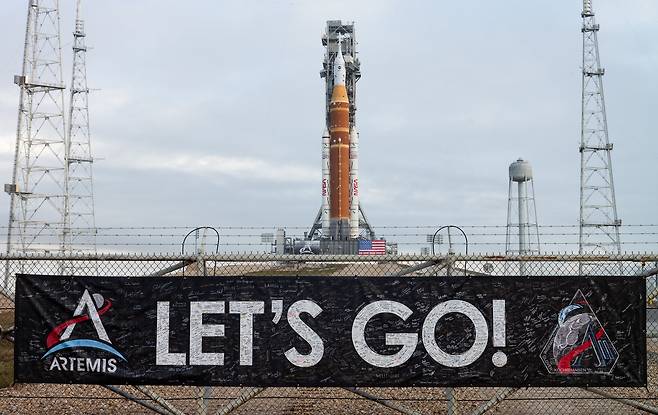 2026년 1월 18일, 플로리다주 NASA 케네디 우주 센터에 세워진 우주발사체 SLS. 여기에 아르테미스 2호 임무를 수행할 우주인이 탑승하는 오리온 우주선이 실렸다. 발사대 주변 울타리에 NASA 직원과 계약업체들의 서명이 담긴 현수막이 걸려 있다./NASA