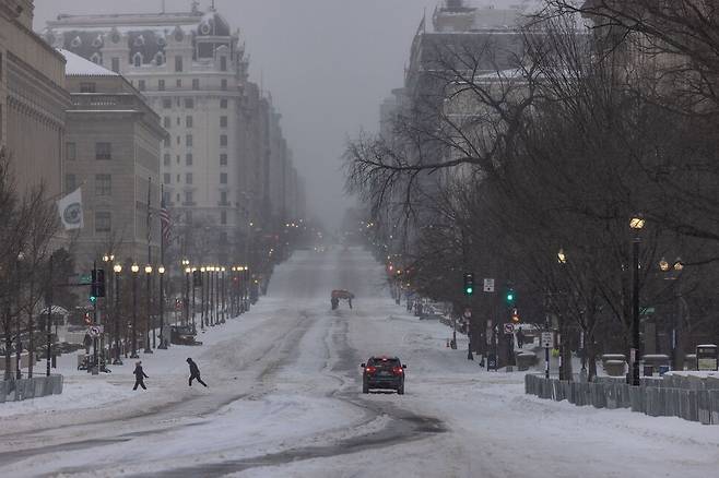 25일(현지시각) 미국 워싱턴에서 차량과 보행자들이 눈 속을 지나 이동하고 있다. 워싱턴/AFP 연합뉴스