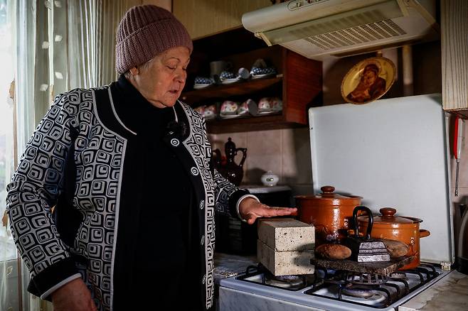 러시아의 미사일·드론 공격으로 핵심 인프라가 타격을 입은 가운데, 키이우 주민인 리우보우 클리멘코(66)가 가스레인지 위에 벽돌이 충분히 달궈졌는지 확인하고 있다. 그는 벽돌을 이용해 난방이 중단된 아파트 온도를 높이고 있다. 로이터연합뉴스