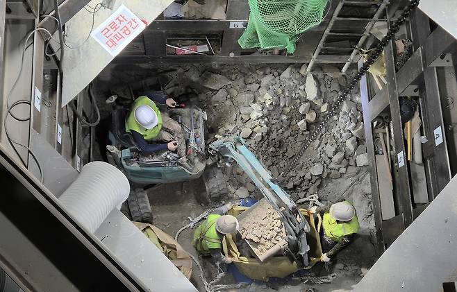 서울지하철 5호선 까치산역 엘리베이터 설치 작업자들이 좁은 공간에서 암반을 부숴서 주어 담고 있다. 서울교통공사 제공