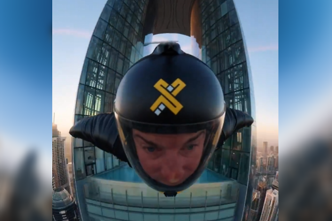 마천루 중앙의 좁은 구멍을 통과하는 윙슈트 선수. 엑스두바이