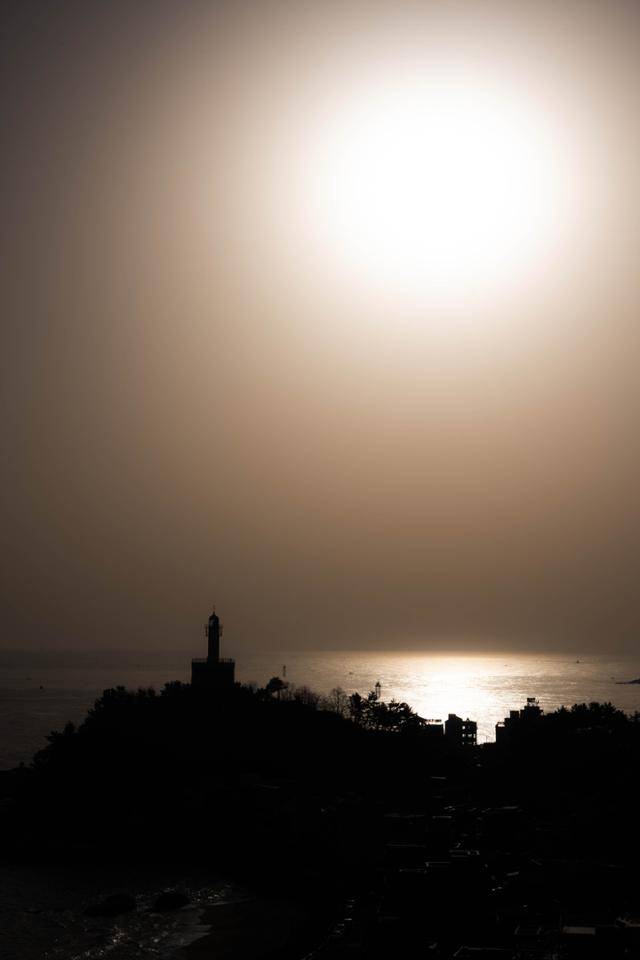 등대해변 인근 건물에서 바라본 속초등대 위로 태양이 떠오르고 있다.